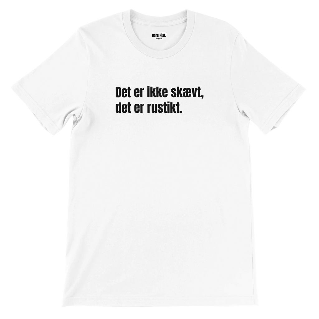 Hvid t-shirt med teksten ”Det er ikke skævt, det er rustikt.”
